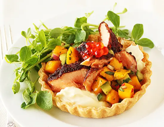 A small pastry with meat and vegetables on top.