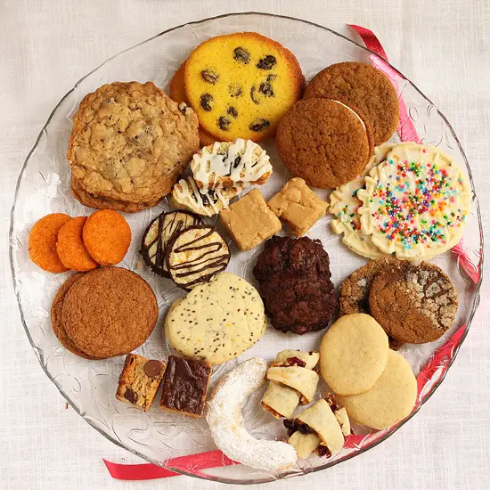 A plate of cookies and other treats on the table.