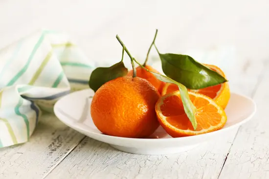 A plate of oranges on top of a table.