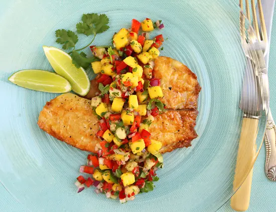 A plate of food with fish and salsa on it.