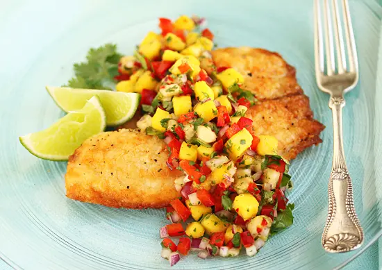 A plate of food with fish and salsa on it.