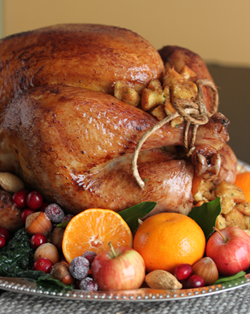 A turkey sitting on top of a pile of fruit.