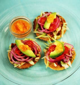 A plate of food with meat, avocado and oranges.