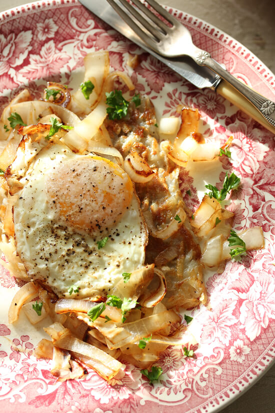 Fried egg with onions and parsley garnish.
