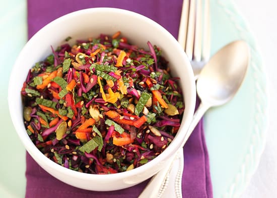 A bowl of salad with colorful vegetables and herbs.