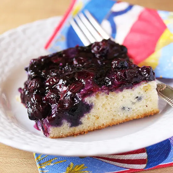 A piece of cake with blueberries on top.