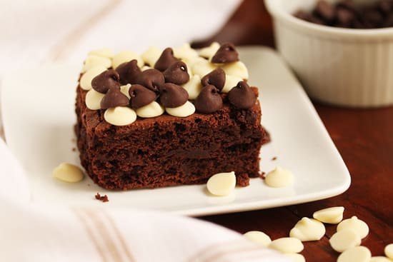A piece of chocolate cake with white and dark chocolate chips on top.