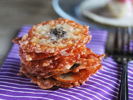 A stack of parmesan cheese covered crackers on top of purple and white striped cloth.