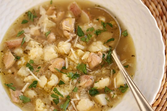 A bowl of soup with meat and potatoes.