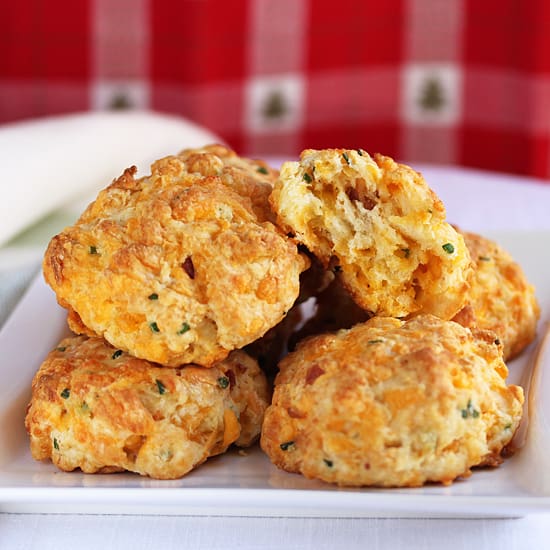 A white plate topped with several biscuits covered in cheese.