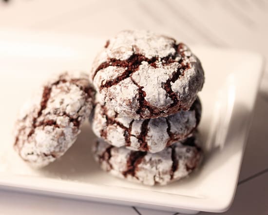 A white plate topped with three chocolate crinkle cookies.