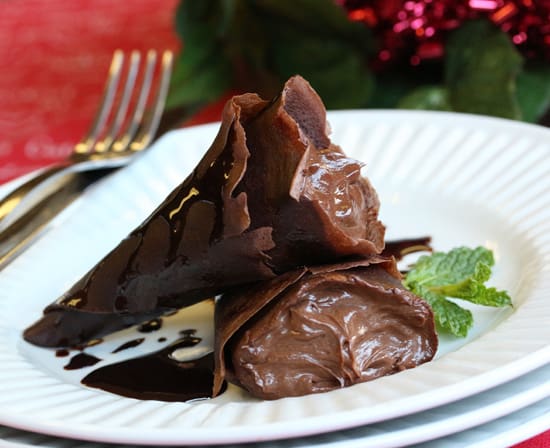 A plate of chocolate cake with mint leaves on top.