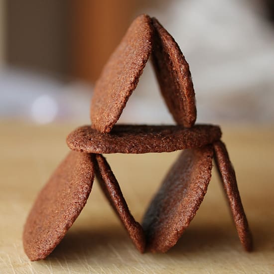 A triangle of chocolate cookies on top of a table.
