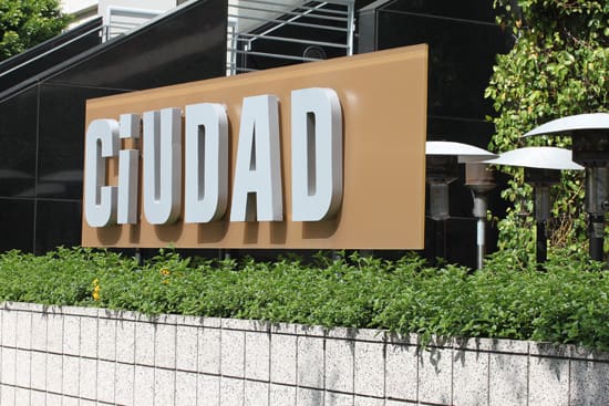 A sign that says ciudad on the side of a building.