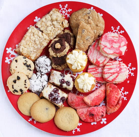 A red plate with cookies and other treats on it.