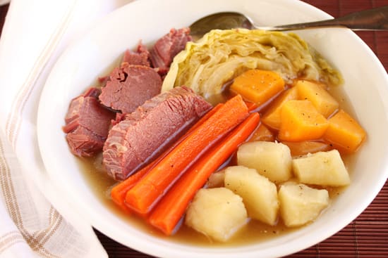 A plate of food with meat, avocado and oranges.
