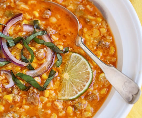 A bowl of soup with corn, onions and lime.