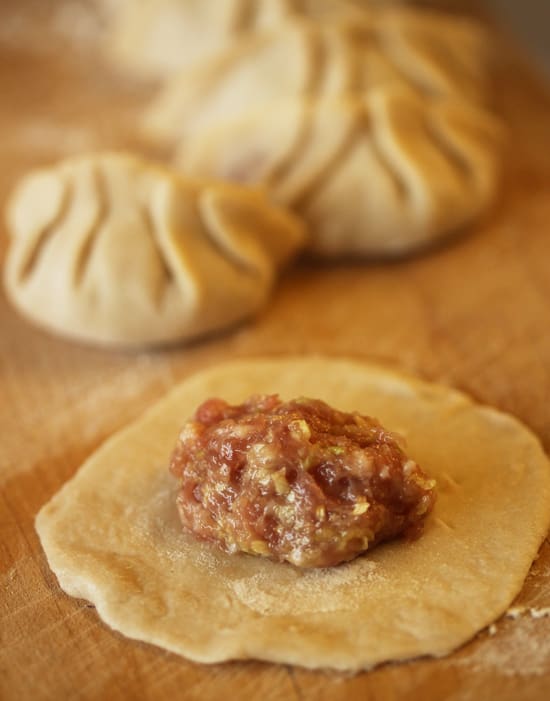A meatball sitting on top of dough next to some other food.