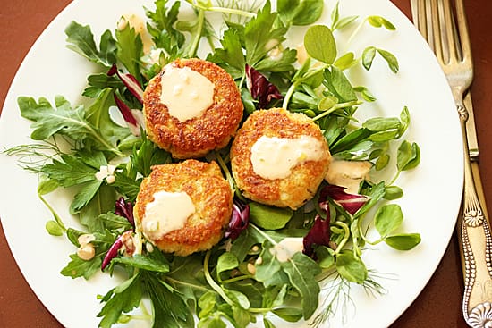 A plate of food with some crab cakes on top