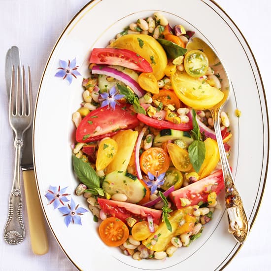 A bowl of salad with corn, tomatoes and red onion.