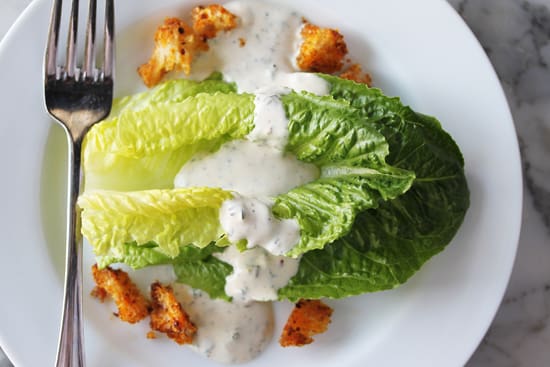 A plate of lettuce and sauce on top of a table.