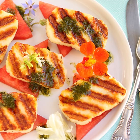 A plate of food with grilled fish and watermelon.