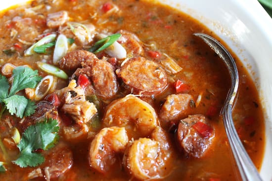 A bowl of stew with shrimp and onions.