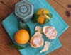 A plate of food with meat, avocado and oranges.