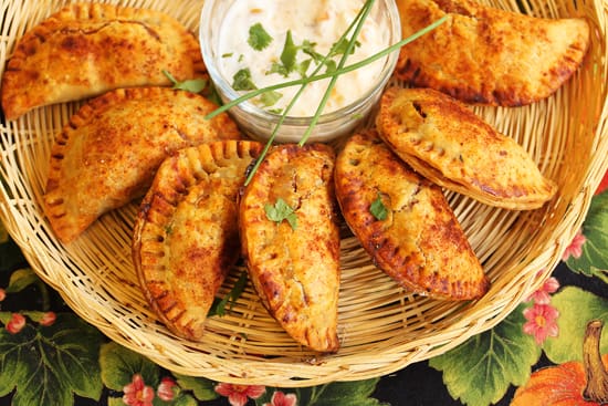 A basket of empanadas with dip on the side.