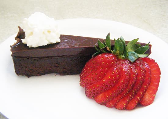 A piece of chocolate cake and some strawberries on a plate.