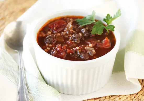 A bowl of chili with parsley on top.