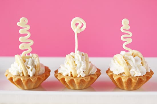 Three small pastries with whipped cream and a candle.
