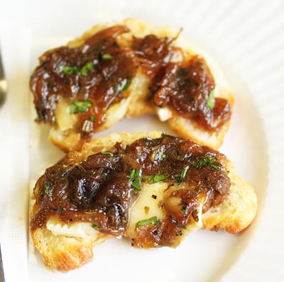 A white plate topped with two pieces of bread covered in sauce.