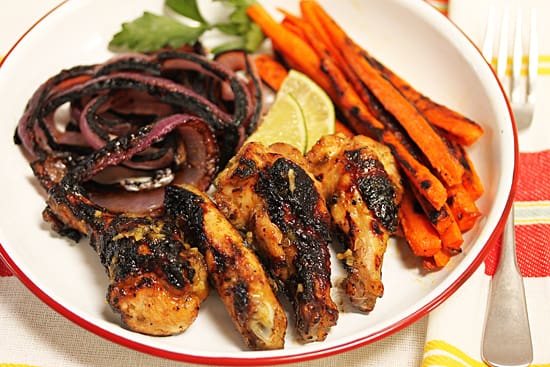 A plate of food with meat, avocado and oranges.