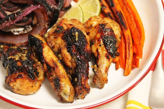 A plate of chicken wings with some vegetables