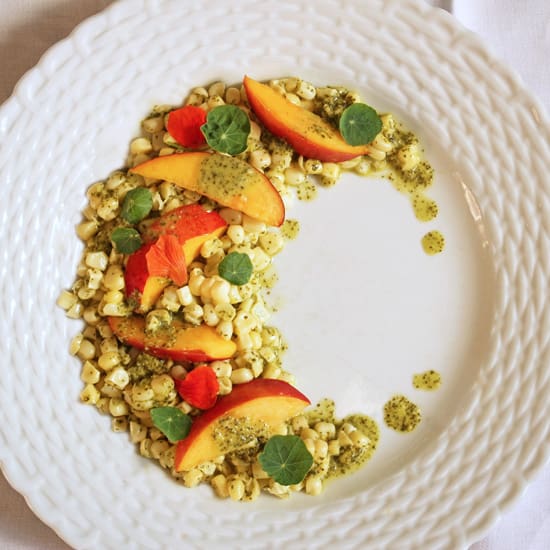 A white plate topped with corn and peaches.