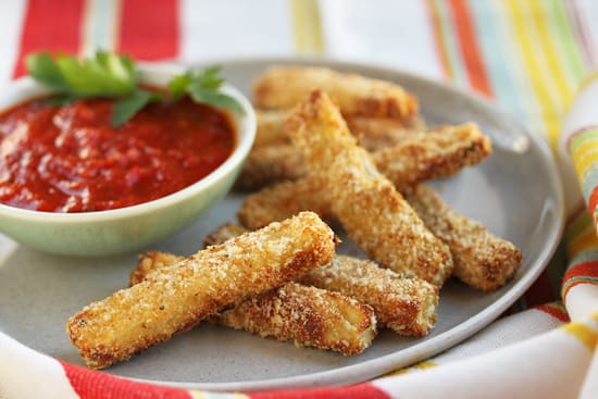 A plate of food with some cheese sticks and sauce