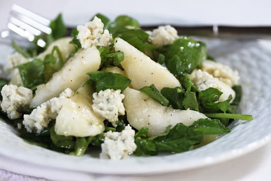 A white plate topped with salad covered in cheese.