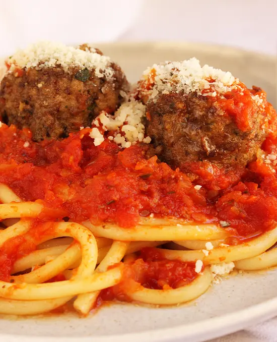 A plate of spaghetti and meatballs with tomato sauce.