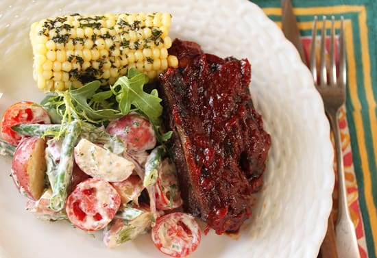 A plate of food with meat, corn and salad.