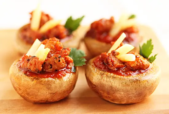 A close up of stuffed mushrooms with meat and cheese