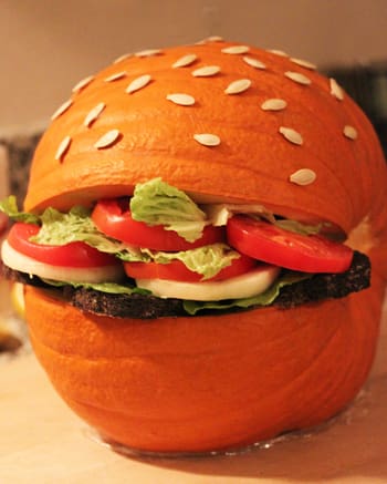A hamburger made out of an orange pumpkin.