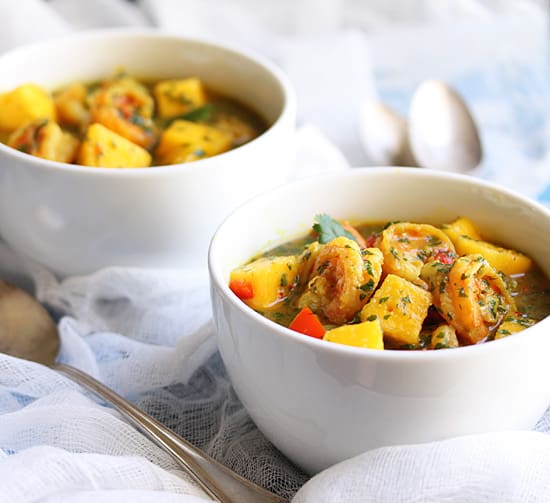 Two bowls of food on a table with spoons.