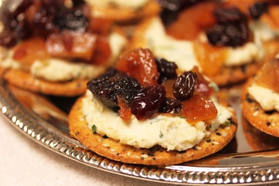 A close up of some crackers with cheese and fruit