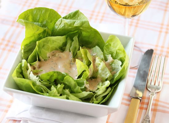 A bowl of lettuce with dressing in it.
