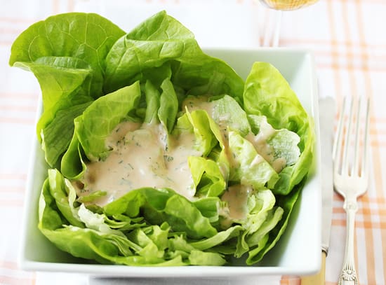 A plate of food with meat, avocado and oranges.