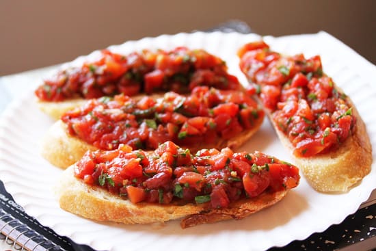 A plate of bruschetta with tomatoes on it.
