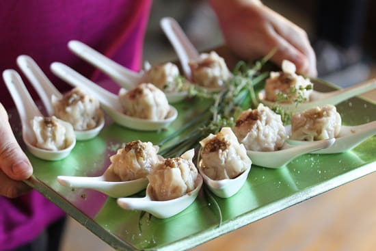 A tray of food with spoons and green leaves.