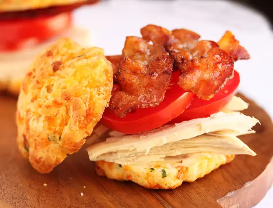 A sandwich with bacon, tomato and cheese on it.