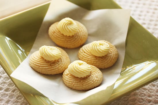 Four cookies with butter on top of a paper.